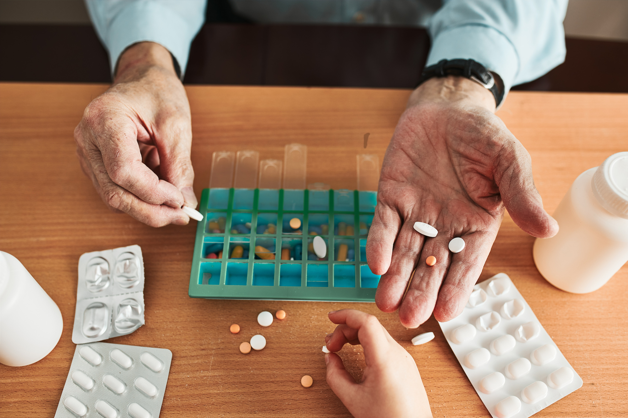 An elderly man holding medication in his hand as part of his medication reminders.