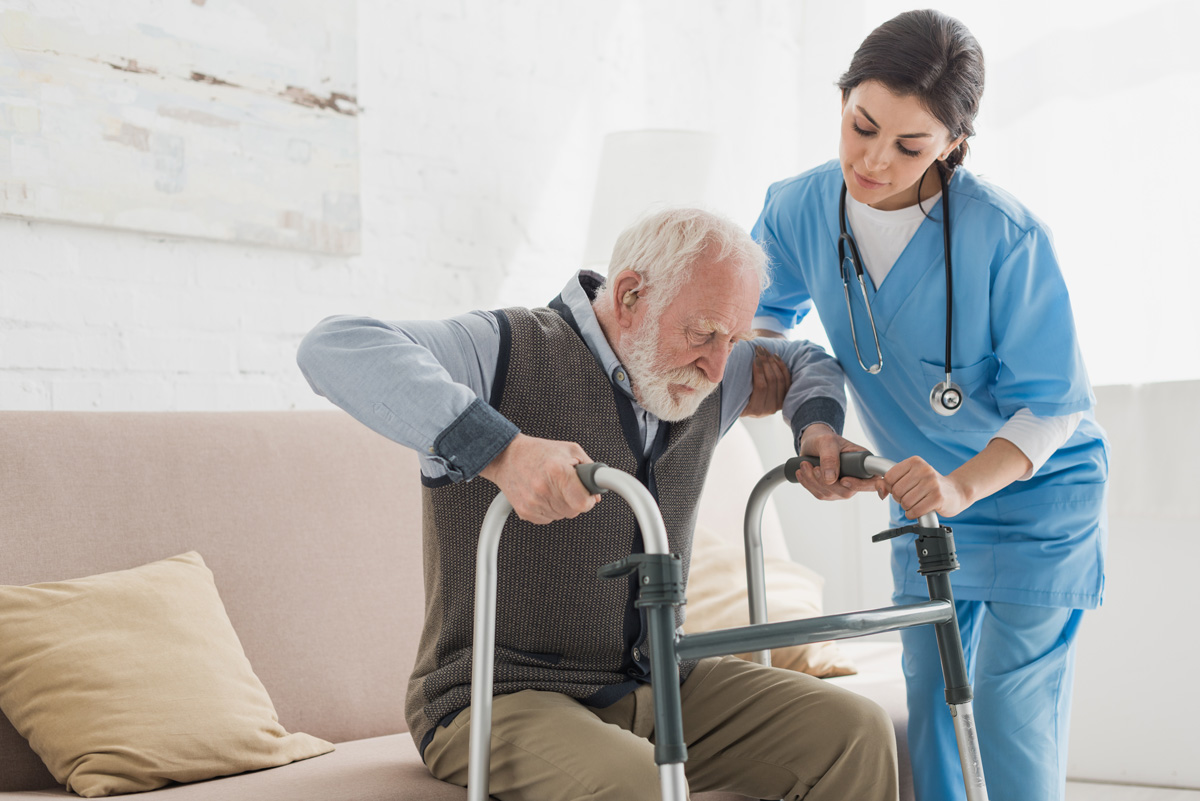 An in-home care professional helping an elderly man stand up in El Paso.