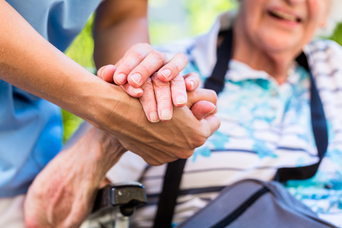 An elderly person and an in-home care nurse holding hands in El Paso.