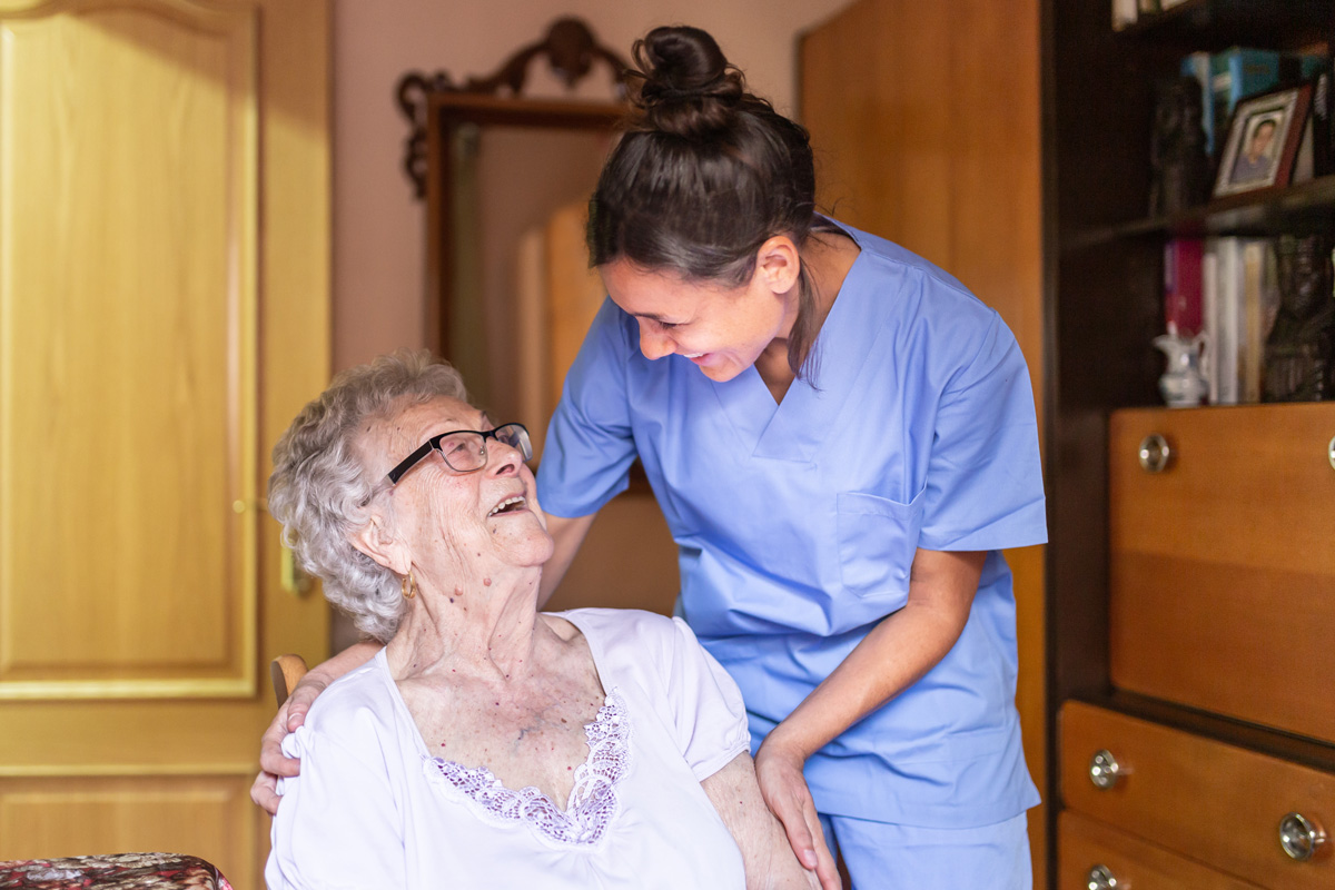 An in-home care nurse laughing with an elderly woman in El Paso.