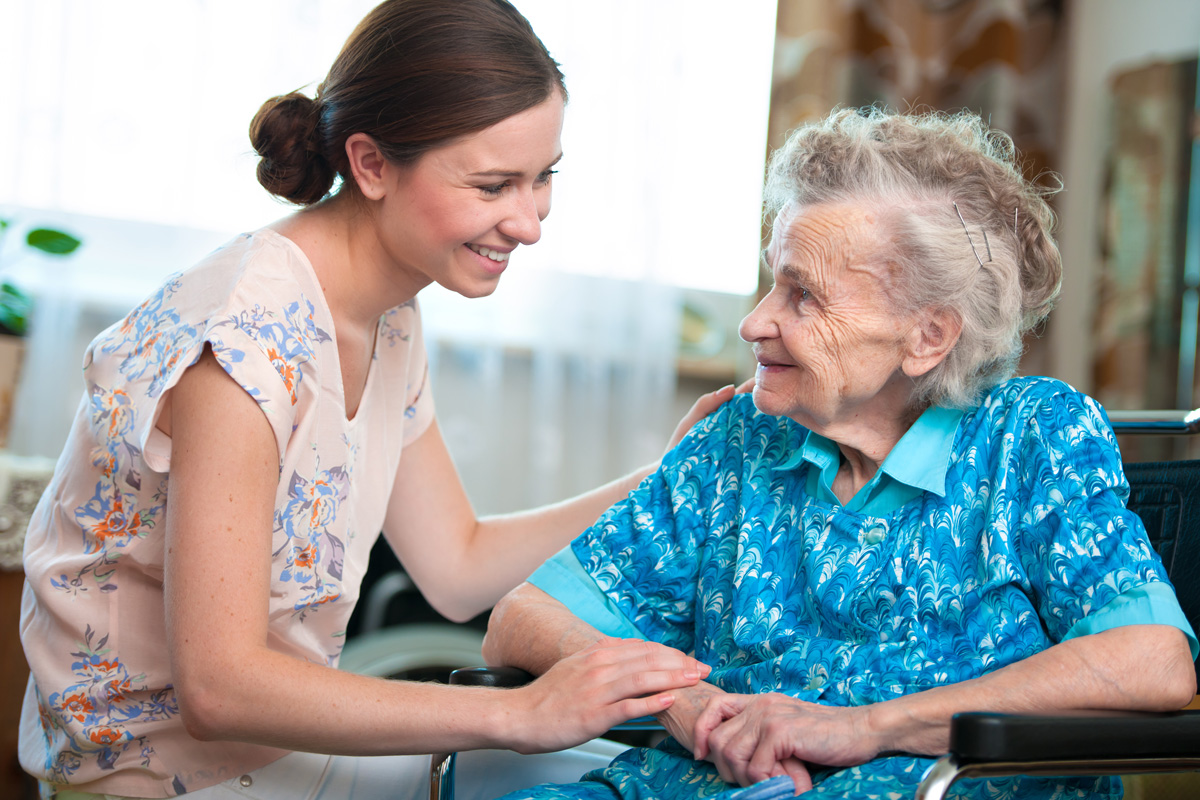 In-home care service professional smiling and spending time with an elderly woman.