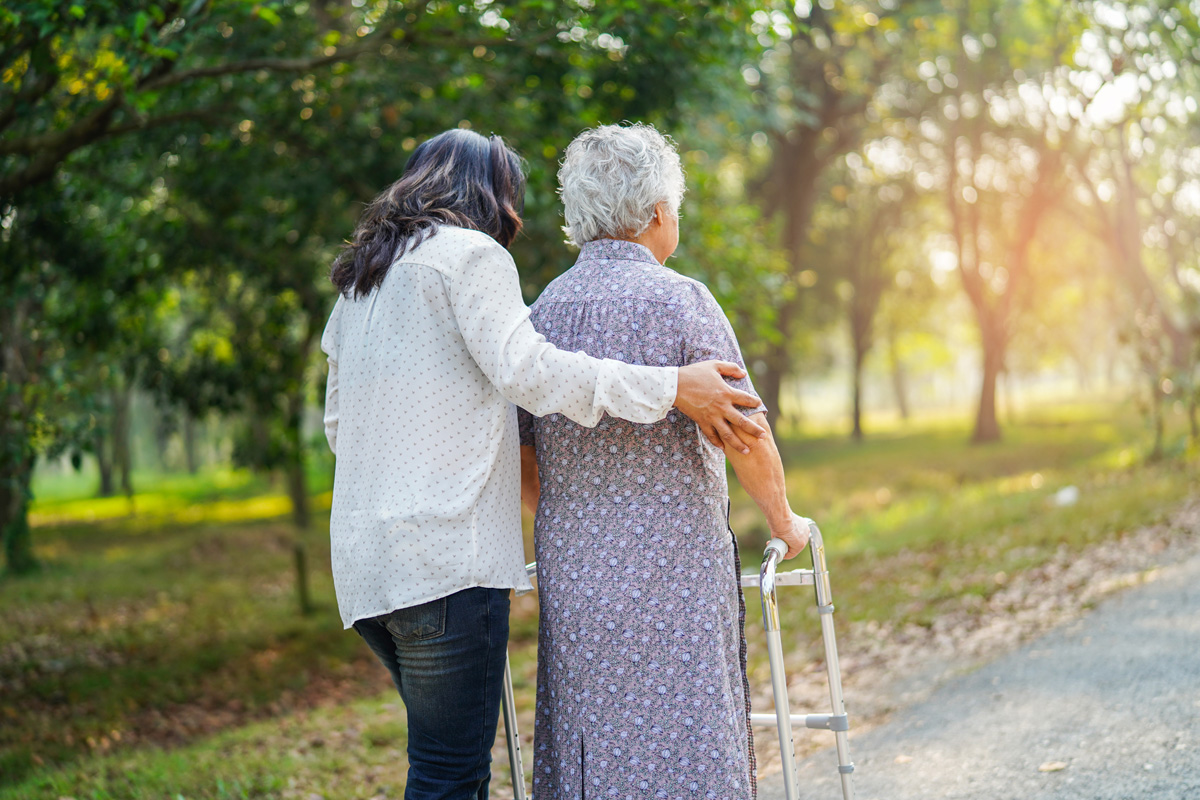 A home care nurse helping an elderly woman walk outside in El Paso.